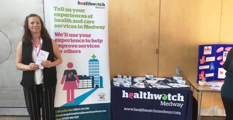 Healthwatch Medway's Debbie standing in front of our stall at the event held by One Voice