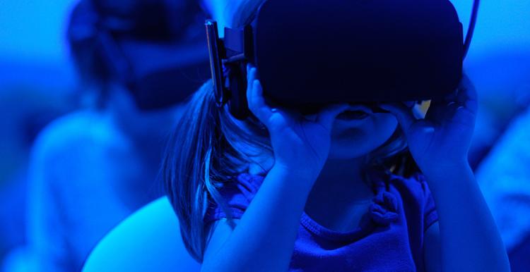 A child wearing a Virtual Reality headset. The lighting in the image is blue for a futuristic effect.