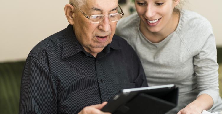 Picture of elderly man getting help to use an Ipad