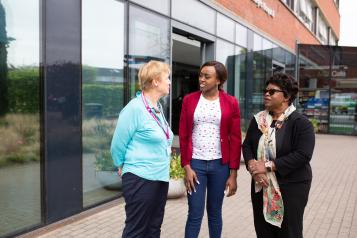 Picture of three women speaking outside a hospital building