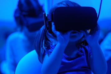 A child wearing a Virtual Reality headset. The lighting in the image is blue for a futuristic effect.