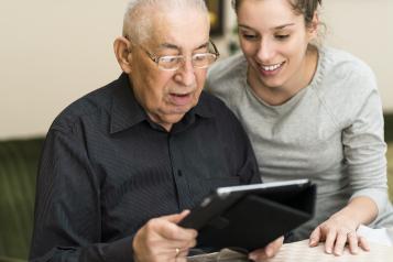 Picture of elderly man getting help to use an Ipad