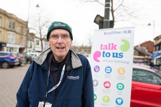 Man standing infront of Healthwatch banner