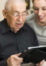 Picture of elderly man getting help to use an Ipad